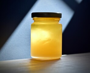 jar fresh rosemary honey on a wooden table illuminated by light through a window