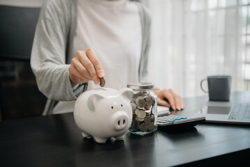 Woman hand holding coin with pig piggy bank. Saving and financial accounts concept.