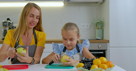 Mother and daughter making fruit salad in kitchen at home