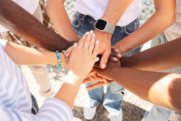 Multicultural people holding hands on top each other, cropped