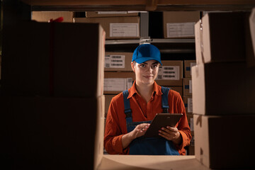 Portrait of a female worker checking inventory using tablet computer, working in a warehouse with...
