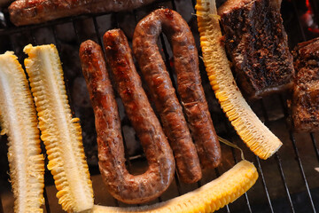 Boerewors sausages on grill with sliced mielies or corn on the cob 