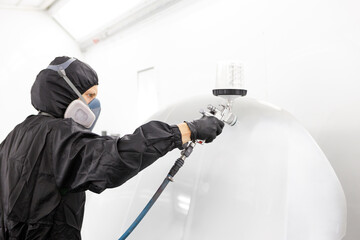 Automotive paint services : Male painters who are skilled in using automotive paint sprayers wearing masks to prevent spray paint dispersion work in a closed spray booth for health and quality work