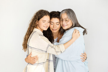 Smiling caucasian teen girl, adult mom and old grandma with closed eyes hugging, enjoy rest and love