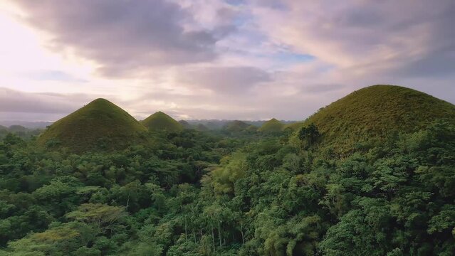 Chocolate Hills at sunset in Bohol Island, Philippines. Aerial drone cinematic shot. Fast forward travelling between hills. Famous tourist destination. Vibrant dusk colors and dramatic cloudy sunset.