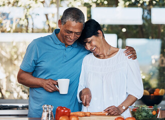 Couple, love and hug while cooking food, cutting vegetables and prepare carrot for salad at home. Mature man, happy woman and embrace in kitchen while making healthy lunch, meal and diet for dinner