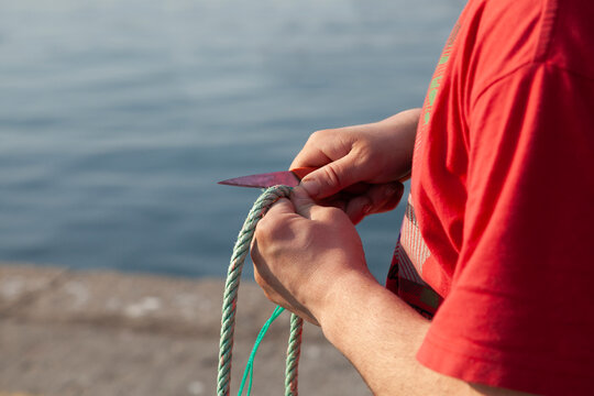 Puerto de Laxe, Man repairing the fishing net with his hands and a knife.
