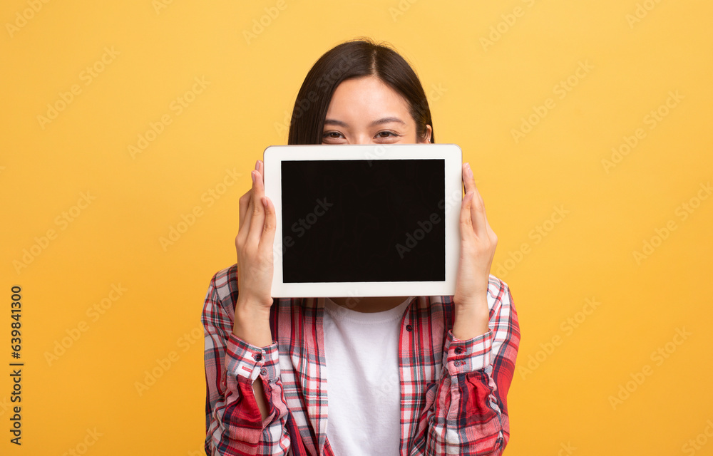 Poster happy japanese lady covering face with empty digital tablet computer, recommending new app or websit