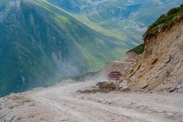 A red pickup truck driving on dirt roads on high plateau roads © alicobanoglu