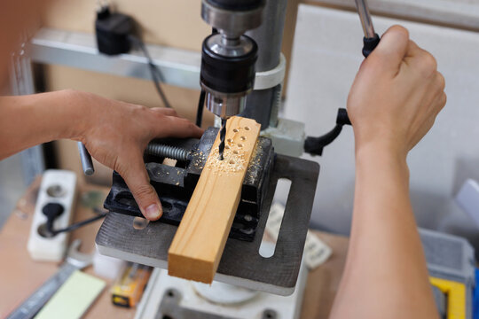 A carpenter's drill makes a hole in a wooden board. Automatic carpentry machine