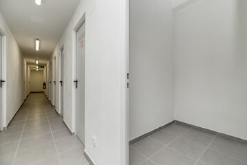 A small empty storage room with white walls and gray tile