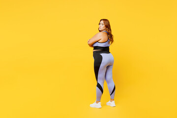 Full body side back view young chubby plus size big fat fit woman wear blue top warm up training hold hands crossed folded isolated on plain yellow background studio home gym. Workout sport concept.