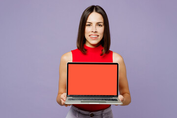 Naklejka premium Young smiling happy cheerful IT woman wears red tank shirt casual clothes hold use work on laptop pc computer with blank screen workspace area isolated on plain pastel light purple background studio.