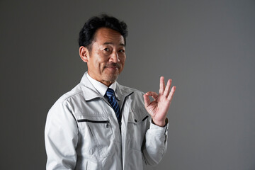 OKポーズをするミドルエイジの作業員　黒背景