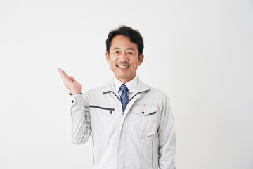 左側を手のひらで指すミドルエイジの作業員　白背景