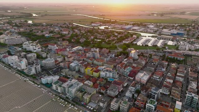 Aerial shot of a Caorle, the Resort sea beach city near to Venice. A beach at Adriatic Sea coastline in a sunset time