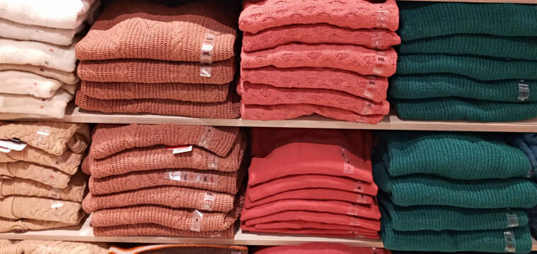 stacks of folded clothes lie on the shelves in the store