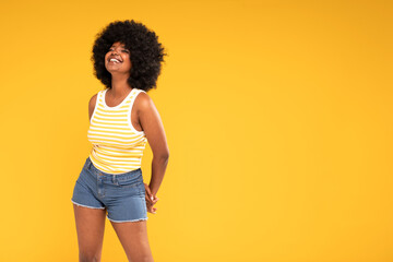 Photo of charismatic cute african american girl in trendy jeans shorts and top laughing happily.