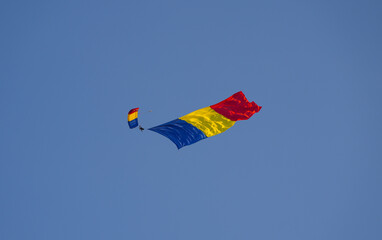 Flag of Romania concept image. Paratroopers with the Romanian flag in flight against clean blue sky.