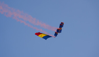 Flag of Romania concept image. Paratroopers with the Romanian flag in flight against clean blue sky.