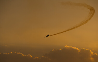 Obraz premium Aerial acrobatics airshow. Ultra light airplanes doing acrobatics in air against amazing sunset sky. Aviation industry concept image.