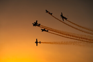 Aerial acrobatics airshow. Ultra light airplanes doing acrobatics in air against amazing sunset sky. Aviation industry concept image.