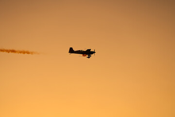 Aerial acrobatics airshow. Ultra light airplanes doing acrobatics in air against amazing sunset sky. Aviation industry concept image.