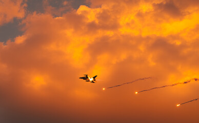 Fighter jet super sonic speed military air planes flying against sunset sky and shooting fire...