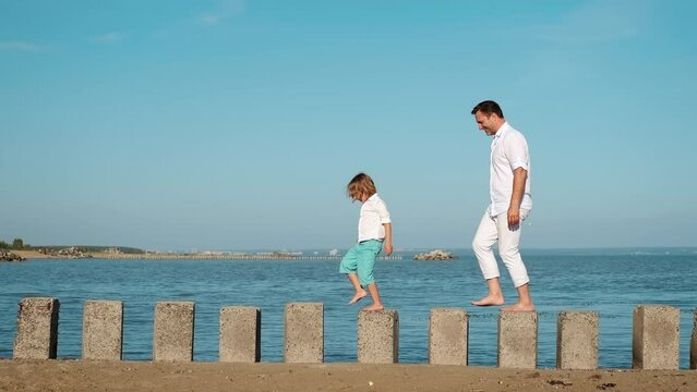 Father and son overcome obstacles playing on the coast of the sea.