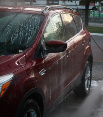 washing a car outside, a red car at a car wash, outdoor