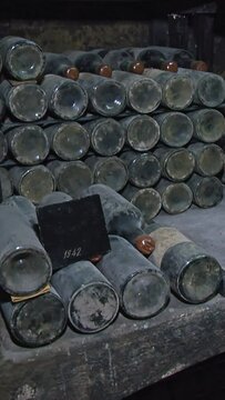 Old Aged Wine Bottles Storage in Dark Rustic Cellar Basement, Stack of Lying Dir
