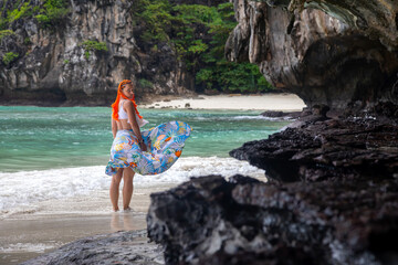 A beautiful girl stands on a sunny sandy beach. The famous Maya Bai. Sunny morning. Beautiful sea.