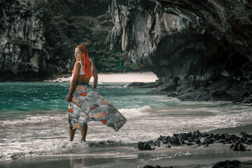 A beautiful girl stands on a sunny sandy beach. The famous Maya Bai. Sunny morning. Beautiful sea.