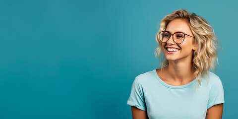 Attractive blond woman wearing blue tshirt and glasses. Isolated on blue background. - obrazy, fototapety, plakaty