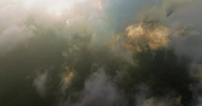 Flying through clouds during sunset light over Munduk village in Bali