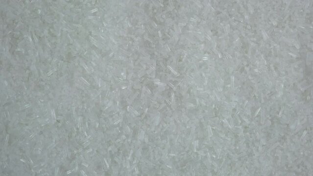 Texture of Monosodium glutamate, MSG powder, close-up. Chinese salt, food additive E621 used in food industry. Oblong white crystalline granules. Fifth taste, umami. Palatability enhancer.