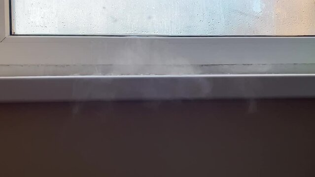 Cold air enters the apartment through crack of window frame. Frosty winter. Window sill with cracks and ice. Heat leakage. Heating problem.