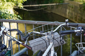 Bicycles parked on a street near distributary of the river. Focus is in the middle of picture on handlebars of bikes, where the background is defocused.