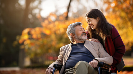 Senior man in wheelchair with his daughter in autumn park