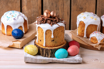 Fototapeta na wymiar Delicious Easter cake with icing, chocolate nest and painted eggs on wooden table. Side view.