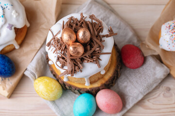 Delicious Easter cake with icing, chocolate nest and painted eggs on wooden table. Side view.
