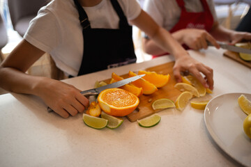 Obraz na płótnie Canvas close-up shot. children's hands cut citrus fruits for making lemonade at a culinary master class