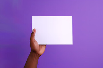 Obraz premium A human hand holding a blank sheet of white paper or card isolated on purple background