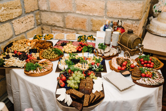 Buffet table. Mini cold snacks, canapes, appetizers with alcohol for public catering. Food on wooden plates, serving board on festive table, corporate food. Party and holiday away in hall restaurant.