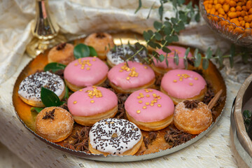 Colorful donuts with icing and sprinkles on the tray, wedding candy bar.