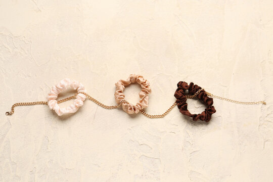 Set of silk scrunchies and necklace on light background