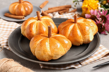 Naklejka na ściany i meble Plate with tasty pumpkin shaped buns on table