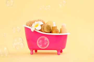 Small bathtub with different bath supplies and soap bubbles on color background