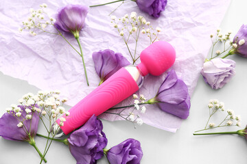 Composition with beautiful flowers and vibrator on white background, closeup