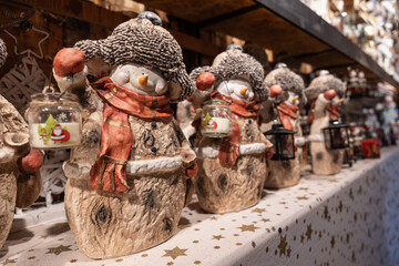 Christmas snowmen with candlesticks stand on a shelf in a street market